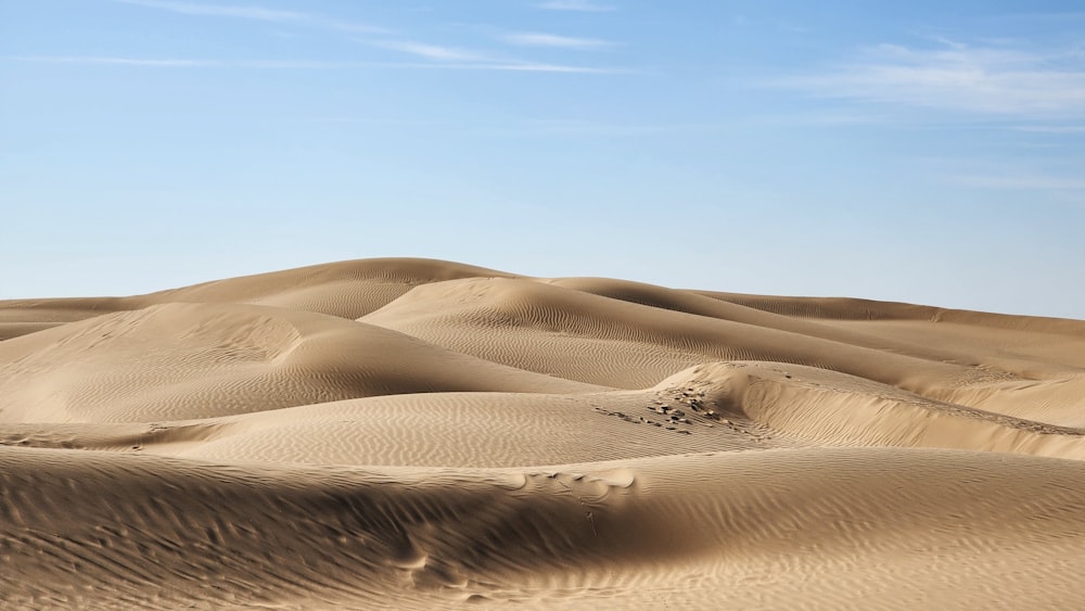 a group of sand dunes with a blue sky in the background