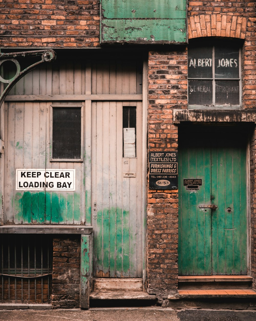 a green door on a brick building with a sign that reads keep clear loading bay