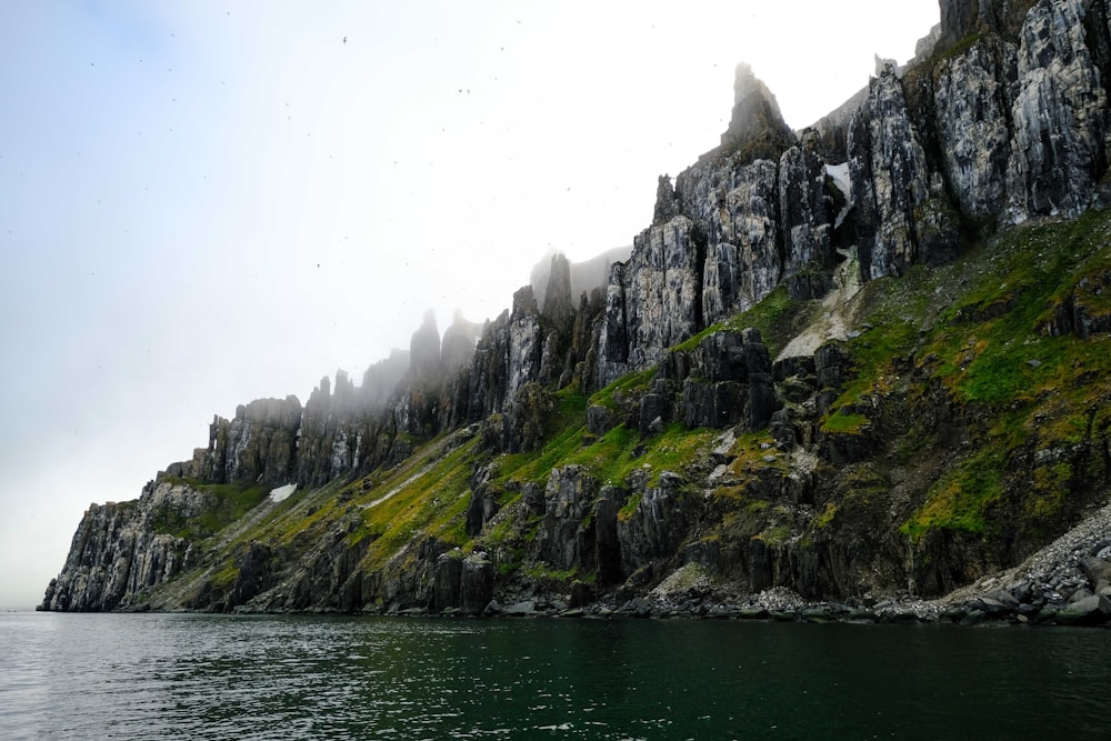 a rocky mountain with a body of water in front of it