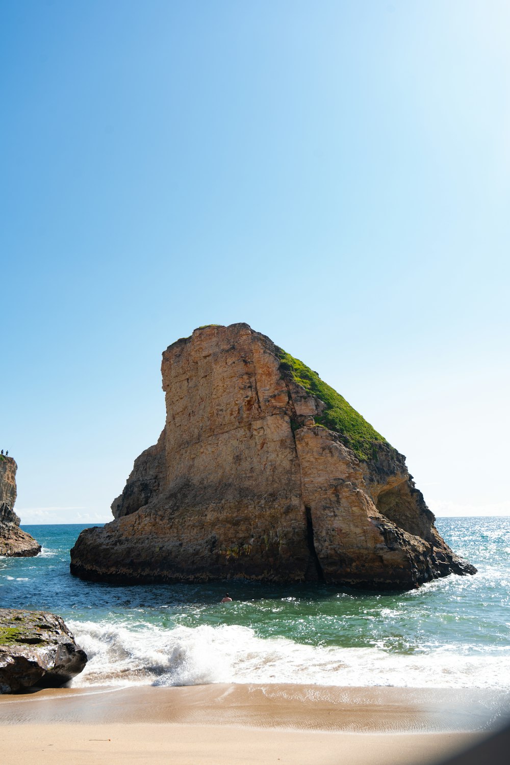 a large rock sitting on top of a sandy beach