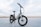 A sleek, modern electric bike stands on a paved surface with a vast, open background. The bike has a sturdy frame, large tires, and is equipped with a suspension fork. The brand name is visible on the frame, and the bike seems ready for both urban and off-road adventures.