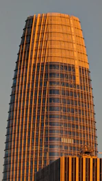 A sleek, modern office tower illuminated by a soft orange glow symbolizing a guiding beacon at dusk.