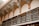 A high-ceilinged room with ornate decorative arches featuring intricate patterns and flourishes. Below the arches, there is a series of wooden shelves with ornately designed metal railings. The shelves are lined with books or files, organized in a neat and orderly manner.