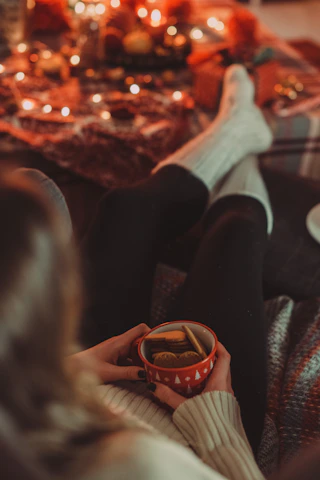 A joyful person enjoying crunchy snacks with a cup of tea in a cozy kitchen setting.