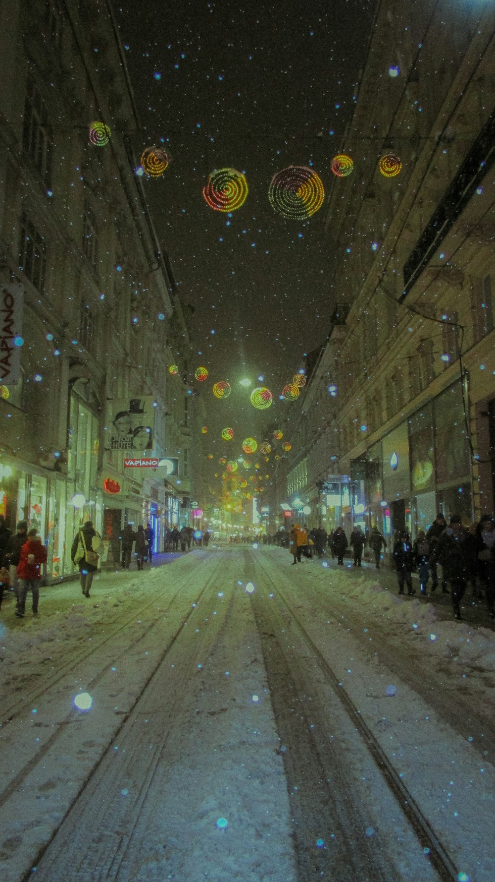 people walking down a snowy street at night