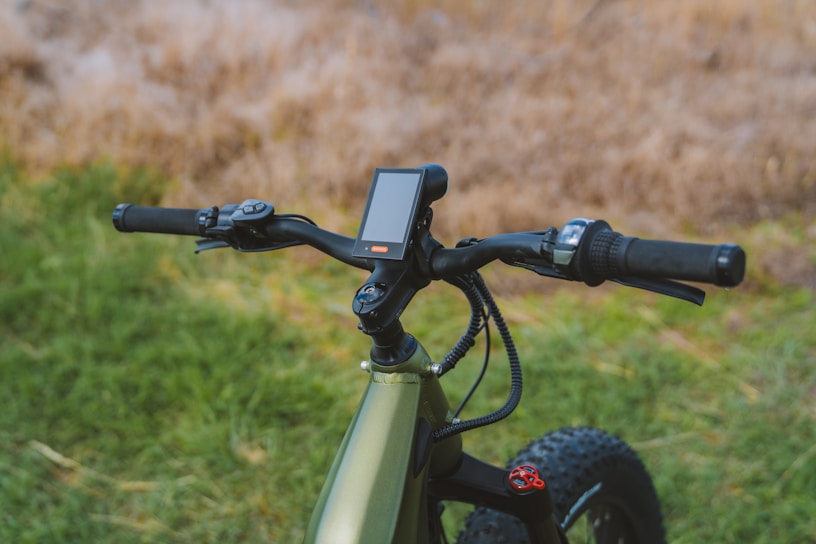 Close-up of an ecolide ebike's sleek handlebars and display panel with factory in the background