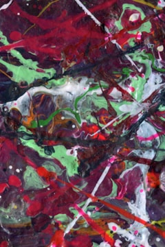 A colorful abstract painting consisting of swirling patterns and bold brushstrokes. The composition is chaotic, with a variety of colors including red, green, white, and dark shades combining to create a dynamic and energetic visual experience. The paint appears to be layered in a way that adds depth and texture.