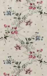 An intricate botanical pattern showcasing delicate pink and blue flowers surrounded by green foliage. The flowers are laid out in a diagonal arrangement across an off-white background embellished with subtle geometric and swirling designs.