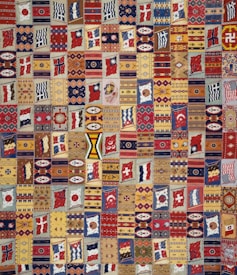 A vibrant patchwork quilt composed of various geometric patterns, flags, and symbolic designs. Each patch is unique and features a range of motifs including stripes, circles, and abstract shapes. The quilt is rich in color and symmetry, capturing a sense of cultural diversity and artistic craftsmanship.