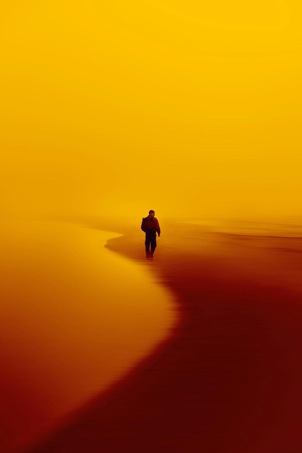 a person walking on a beach at sunset