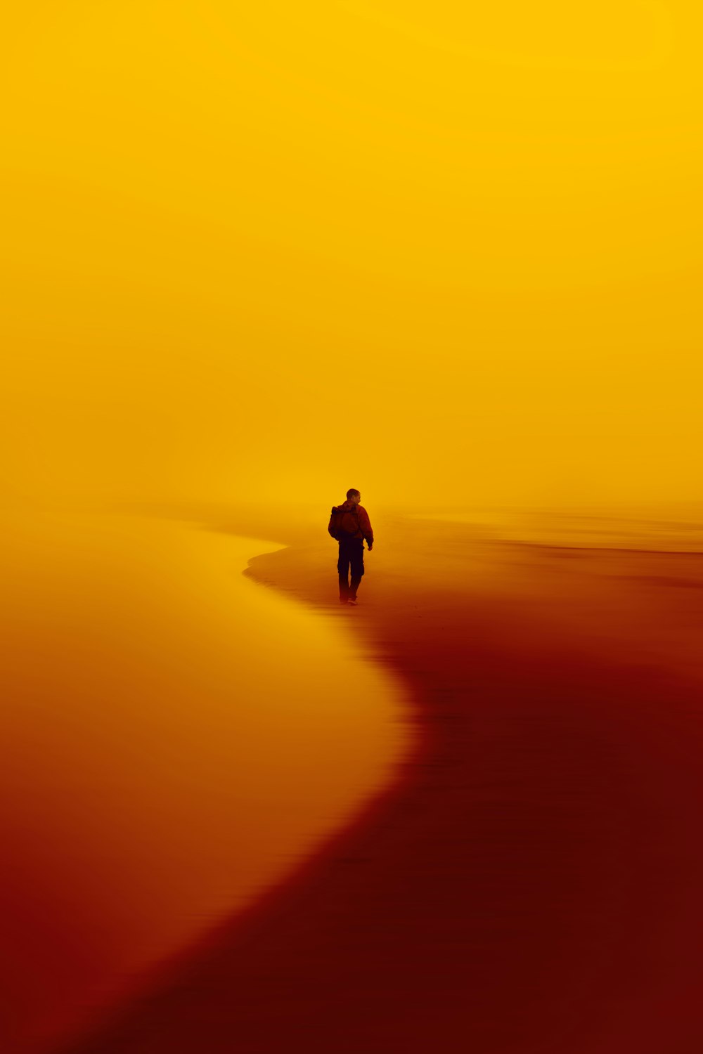 uma pessoa caminhando em uma praia ao pôr do sol
