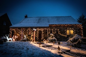 A cozy suburban home wrapped in warm white LED lights outlining the roof and windows, with a glowing wreath on the front door.
