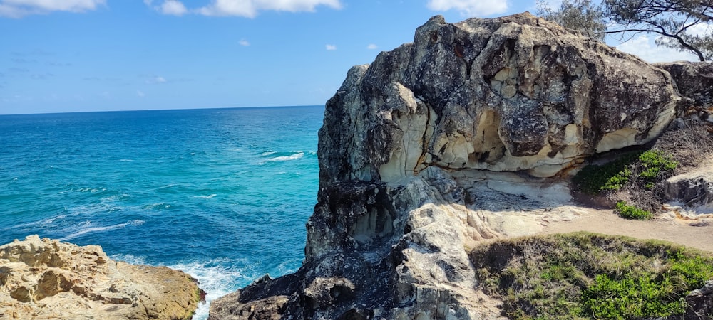 a rocky cliff overlooks the ocean on a sunny day