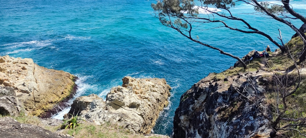 a group of people standing on top of a cliff next to the ocean