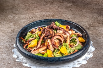 Close-up of a colorful plate featuring octopus salad with herbs and olive oil.