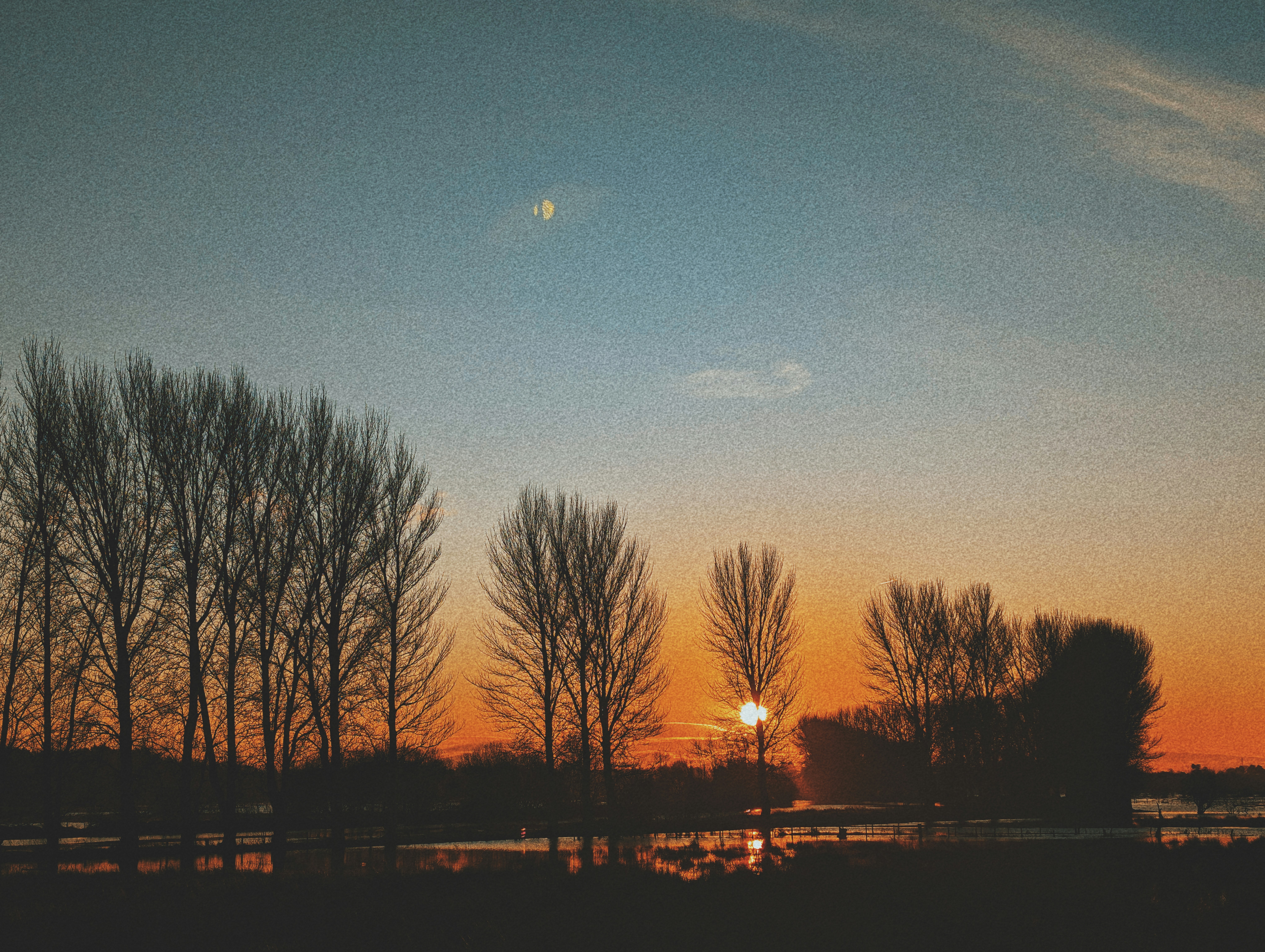 the sun is setting behind some trees