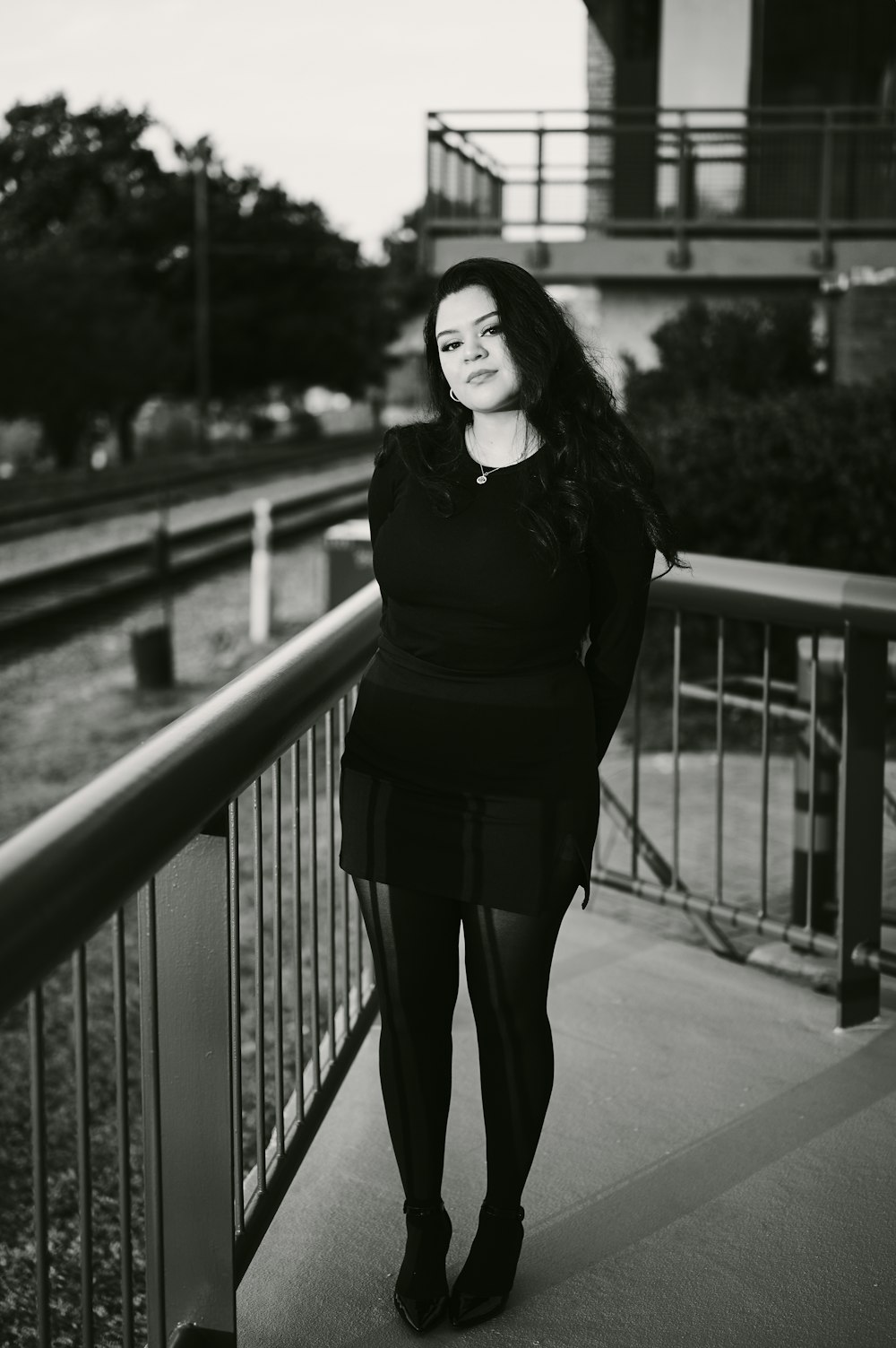 a black and white photo of a woman standing on a balcony