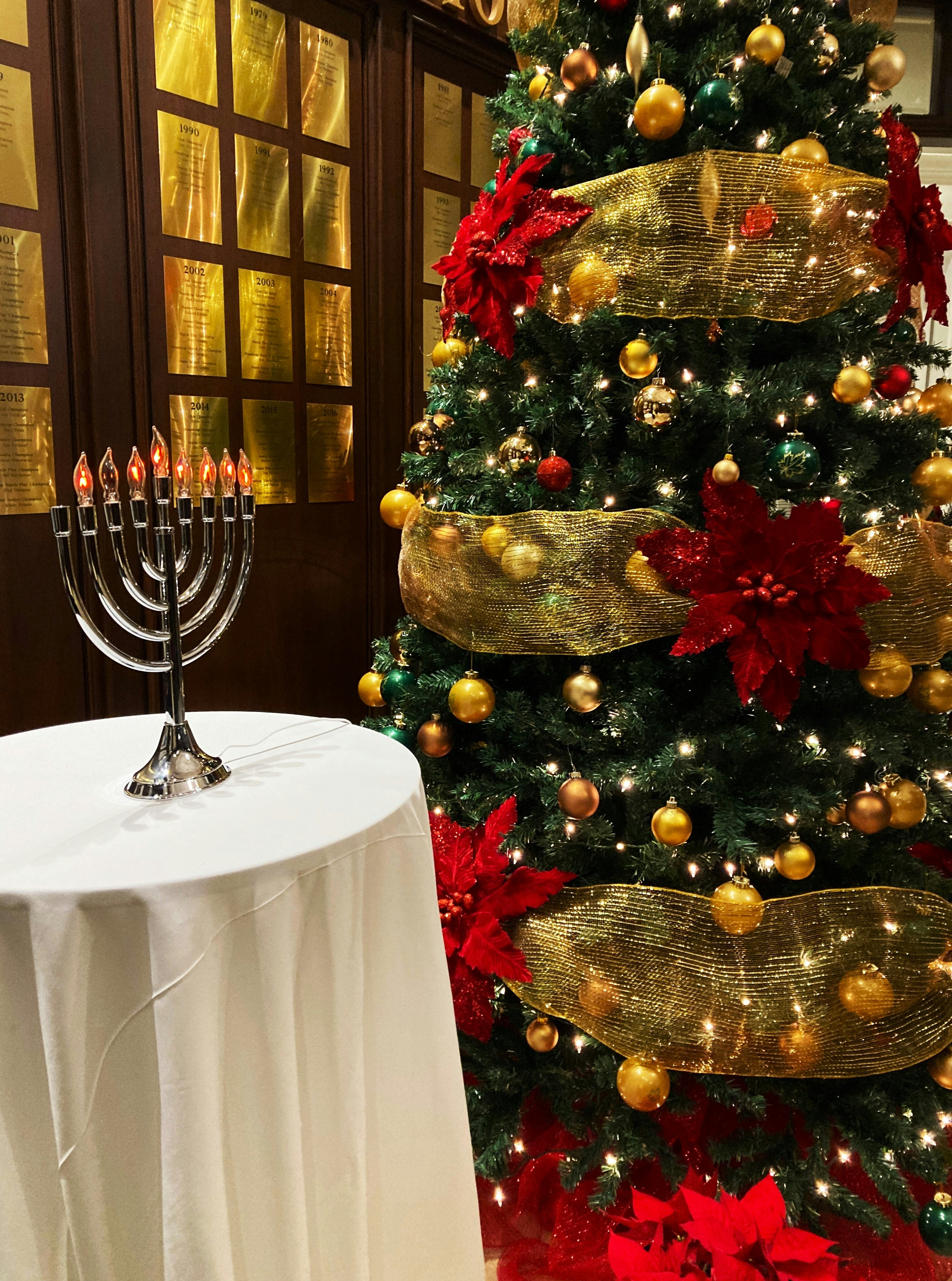 Uma árvore de Natal com uma menorá acesa ao lado