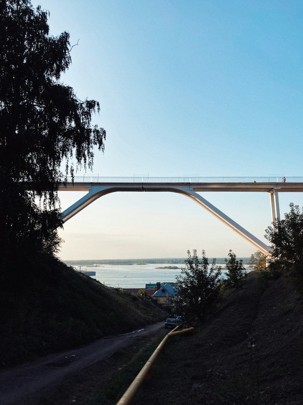 a bridge over a dirt road with a body of water in the background