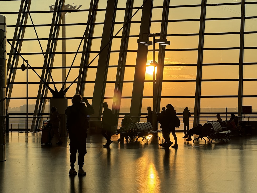 a group of people standing around a terminal at sunset,