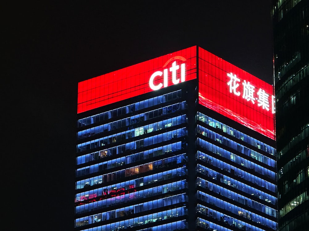 Um prédio alto com uma placa iluminada do Citi ao lado