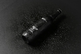 A sleek neon-lit bottle of cold beer with condensation droplets glowing against a dark urban backdrop.