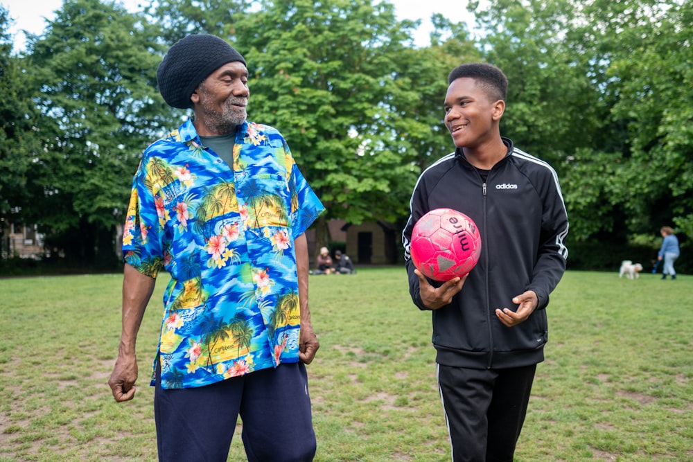 a man holding a soccer ball next to another man