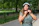 Smiling woman wearing a bicycle helmet in an urban park setting