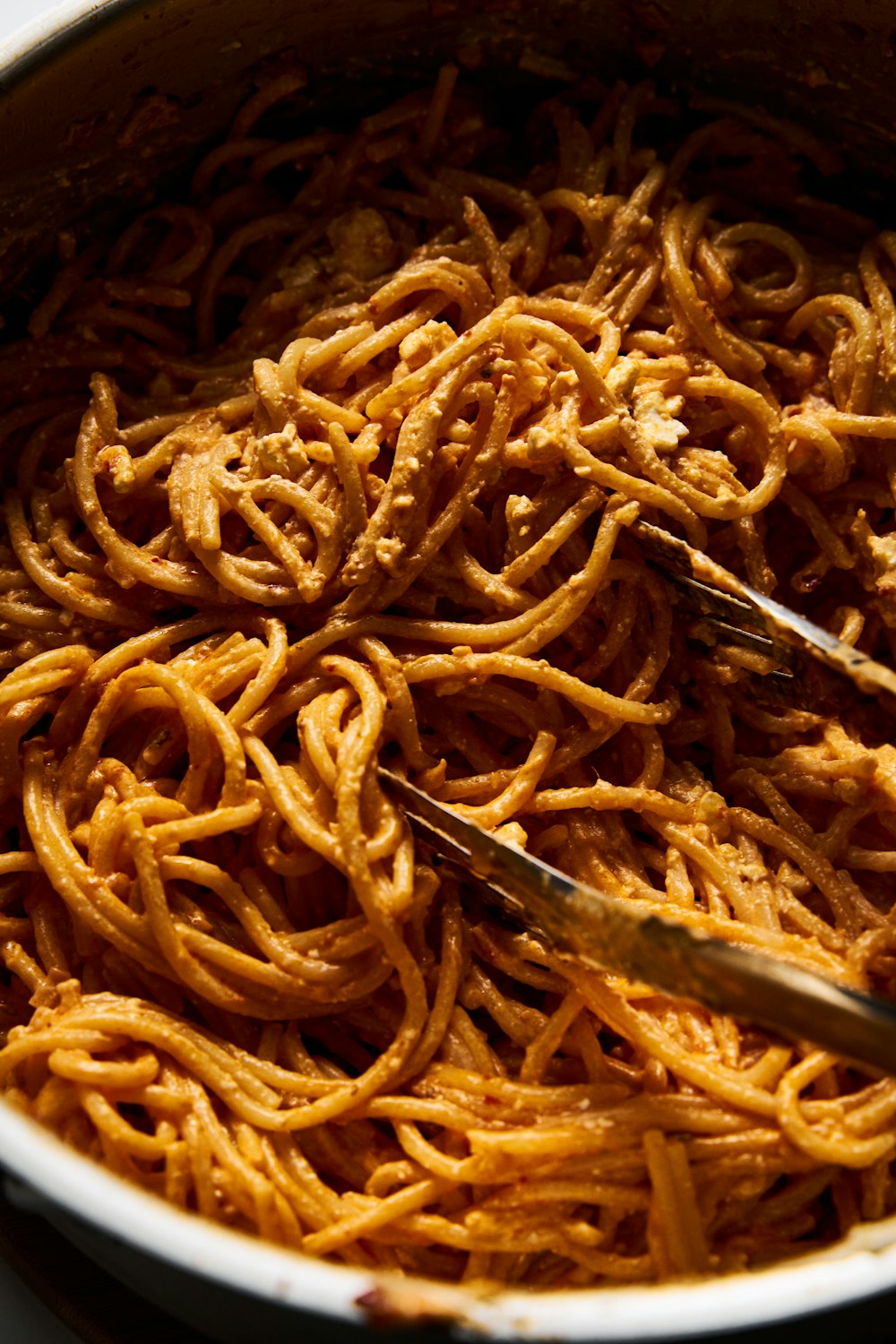 a bowl of spaghetti with a pair of tongs in it
