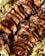 Slices of cooked meat are neatly arranged, glistening with a dark, savory sauce and placed on a bed of fresh, crisp lettuce leaves.