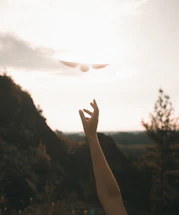 A glowing celestial hand reaching out towards a shimmering starry sky.