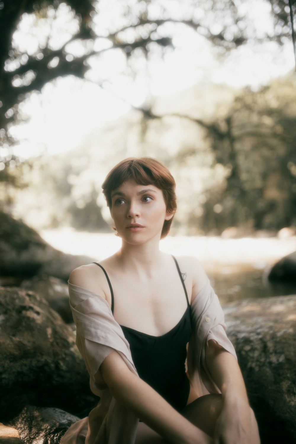 a woman sitting on a rock in the woods