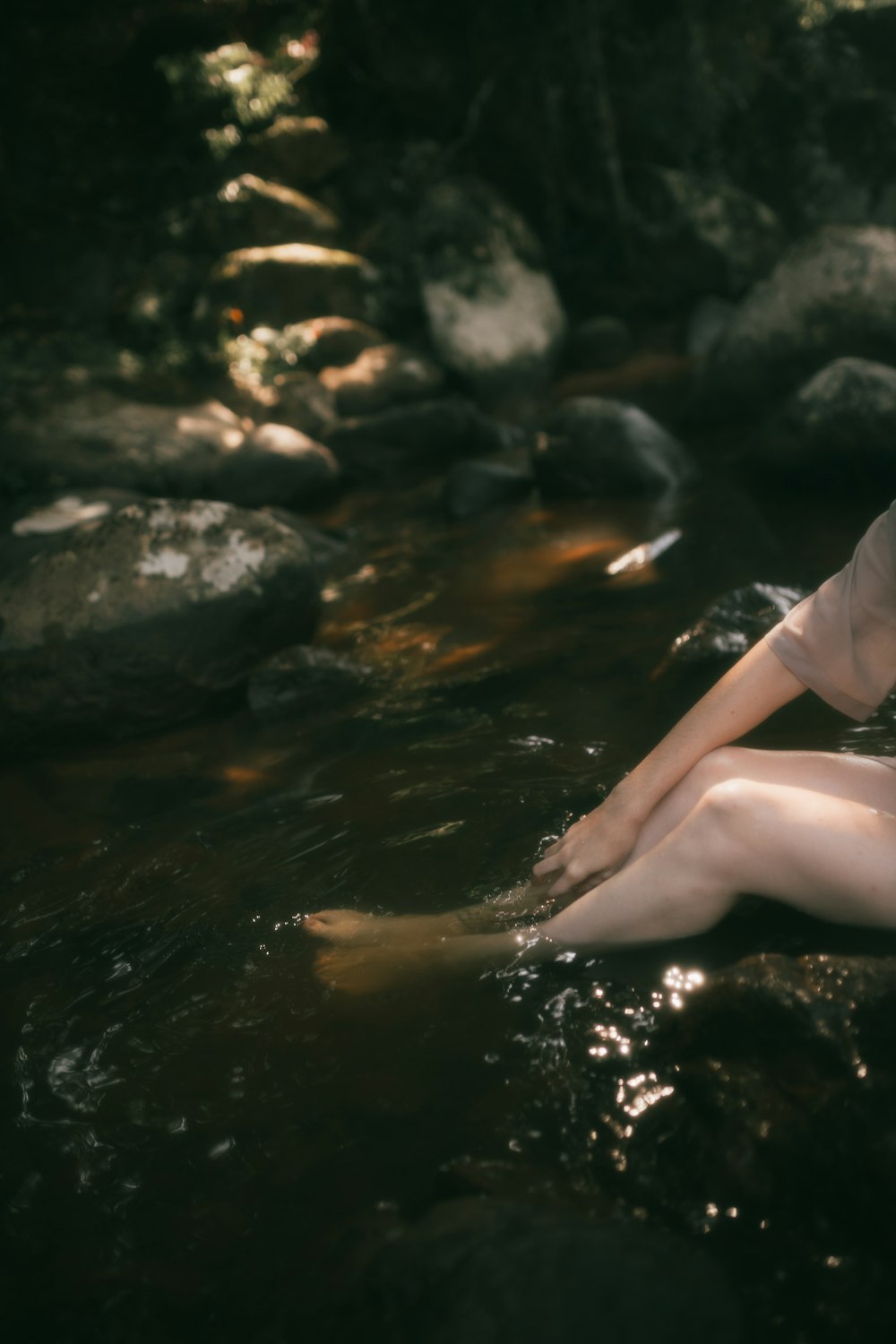 a woman sitting on a rock in the water