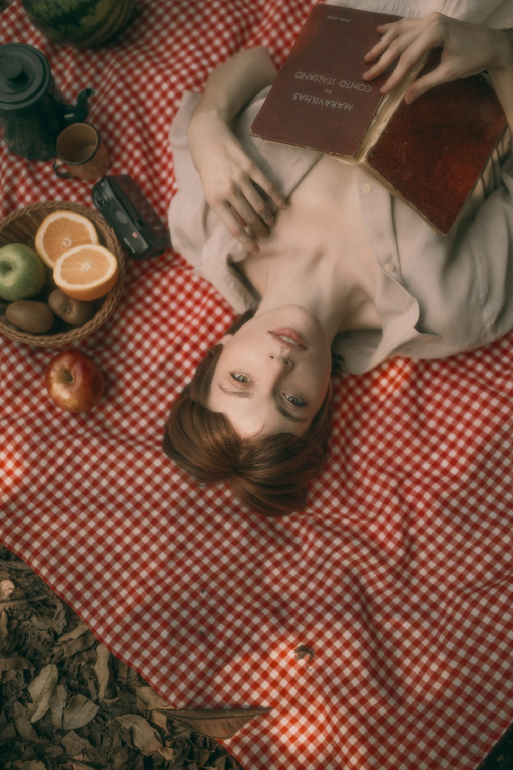 a woman laying on top of a red and white checkered blanket