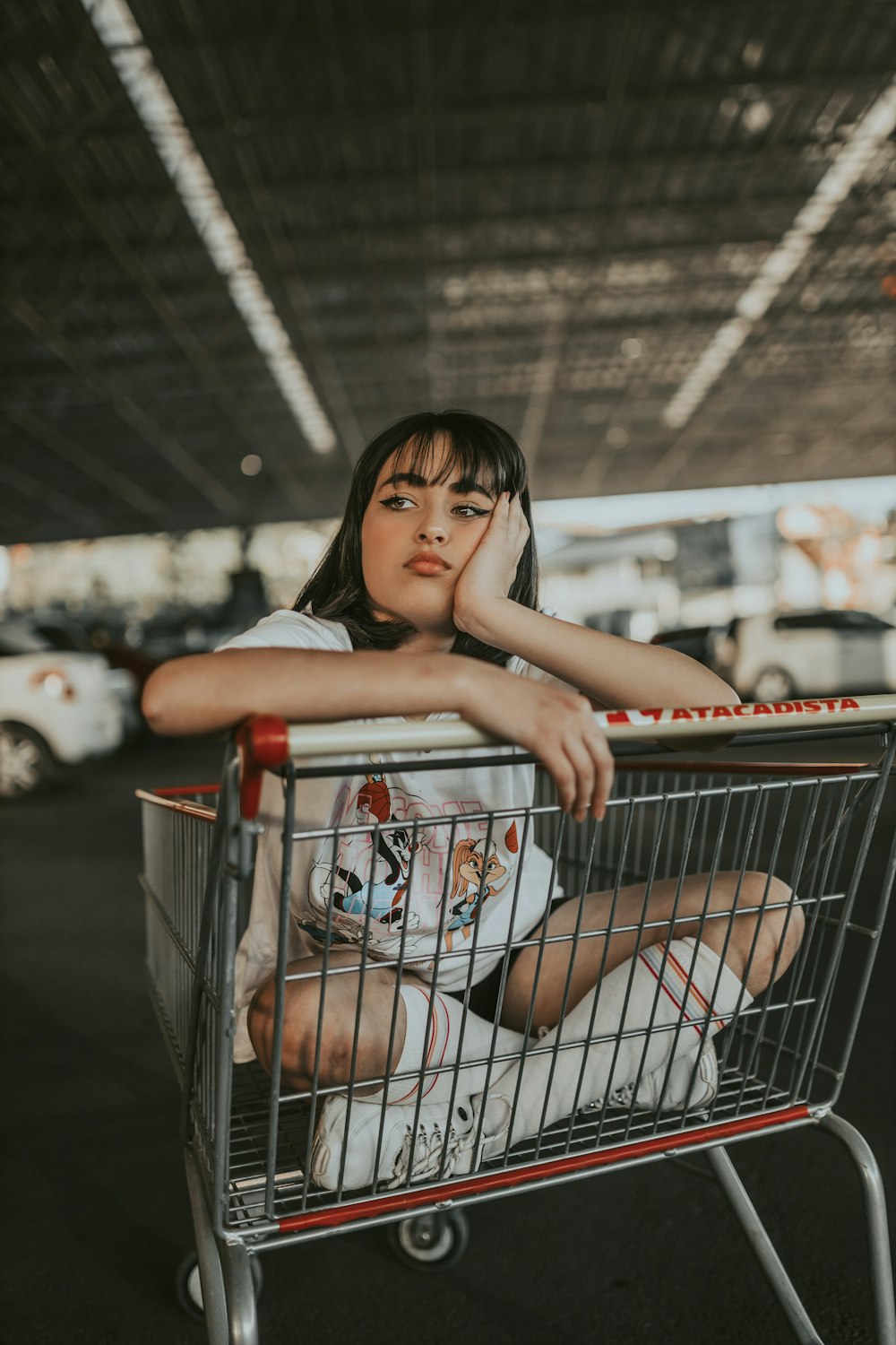 a woman sitting in a shopping cart with her hand on her face