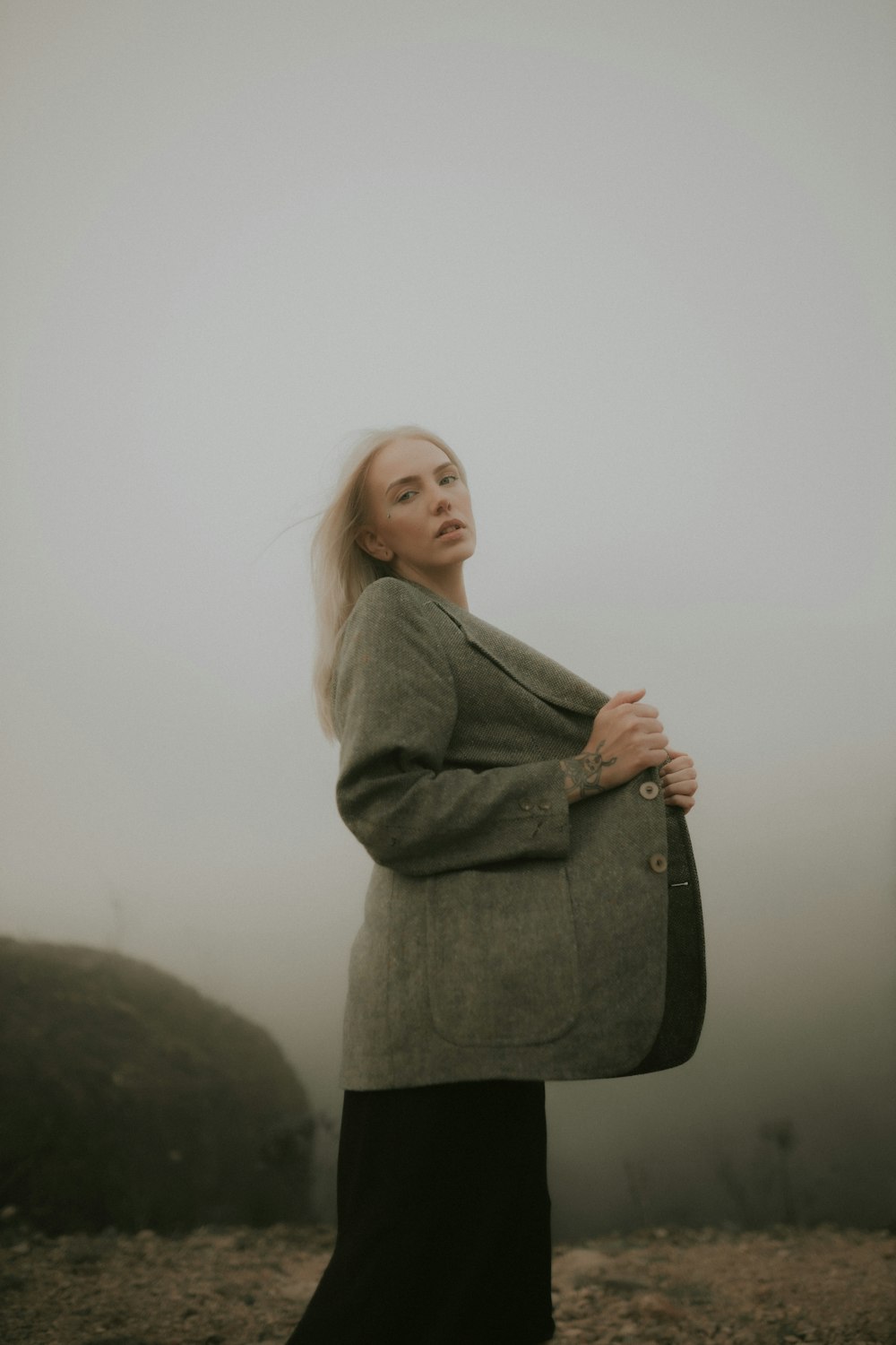 une femme debout dans le brouillard, les bras croisés