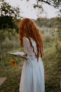 a woman in a white dress holding a sunflower