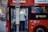 A person is stepping off a red double-decker bus with the destination sign '31 White City Bus Station.' There is a sign indicating it's an alighting point only. The bus is parked on a city street with buildings in the background.