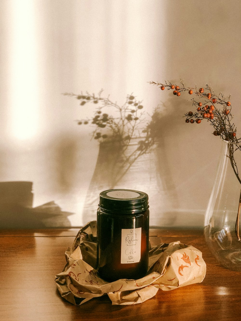 a jar of honey sitting on a table next to a vase of flowers