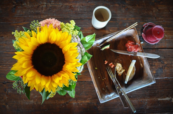 A bright centerpiece featuring sunflowers and daisies set on a wooden table.