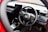The interior of a car showcasing a steering wheel with the Honda logo prominently displayed. The dashboard is modern with digital screens and various control buttons. The surrounding area includes a gear shift and other car controls, suggesting a high-tech, contemporary vehicle interior.