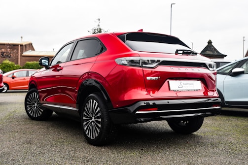 A sleek red SUV parked in a sunlit dealership lot, showcasing its shiny exterior and modern design.