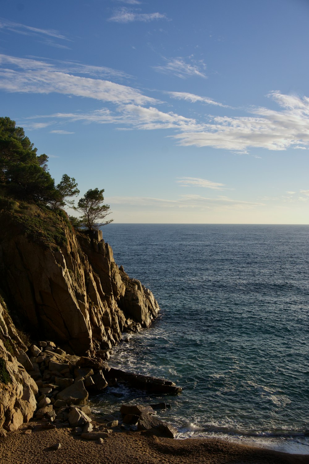 a rocky cliff overlooks the ocean on a sunny day