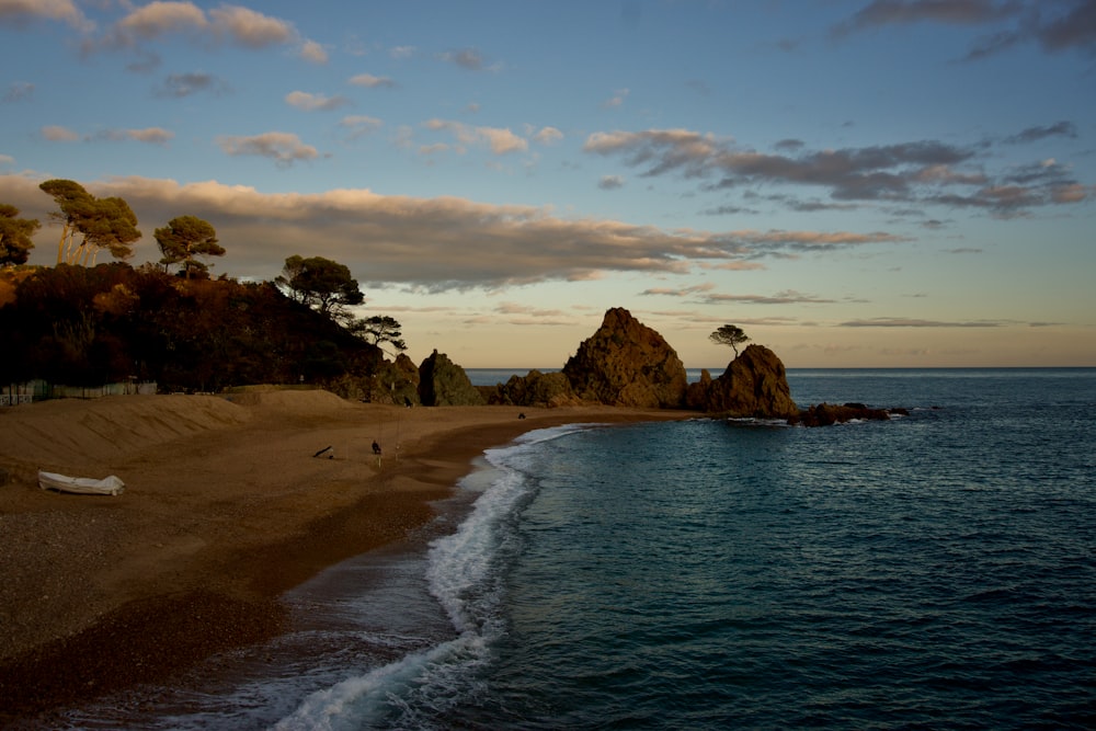 a sandy beach next to the ocean under a cloudy sky