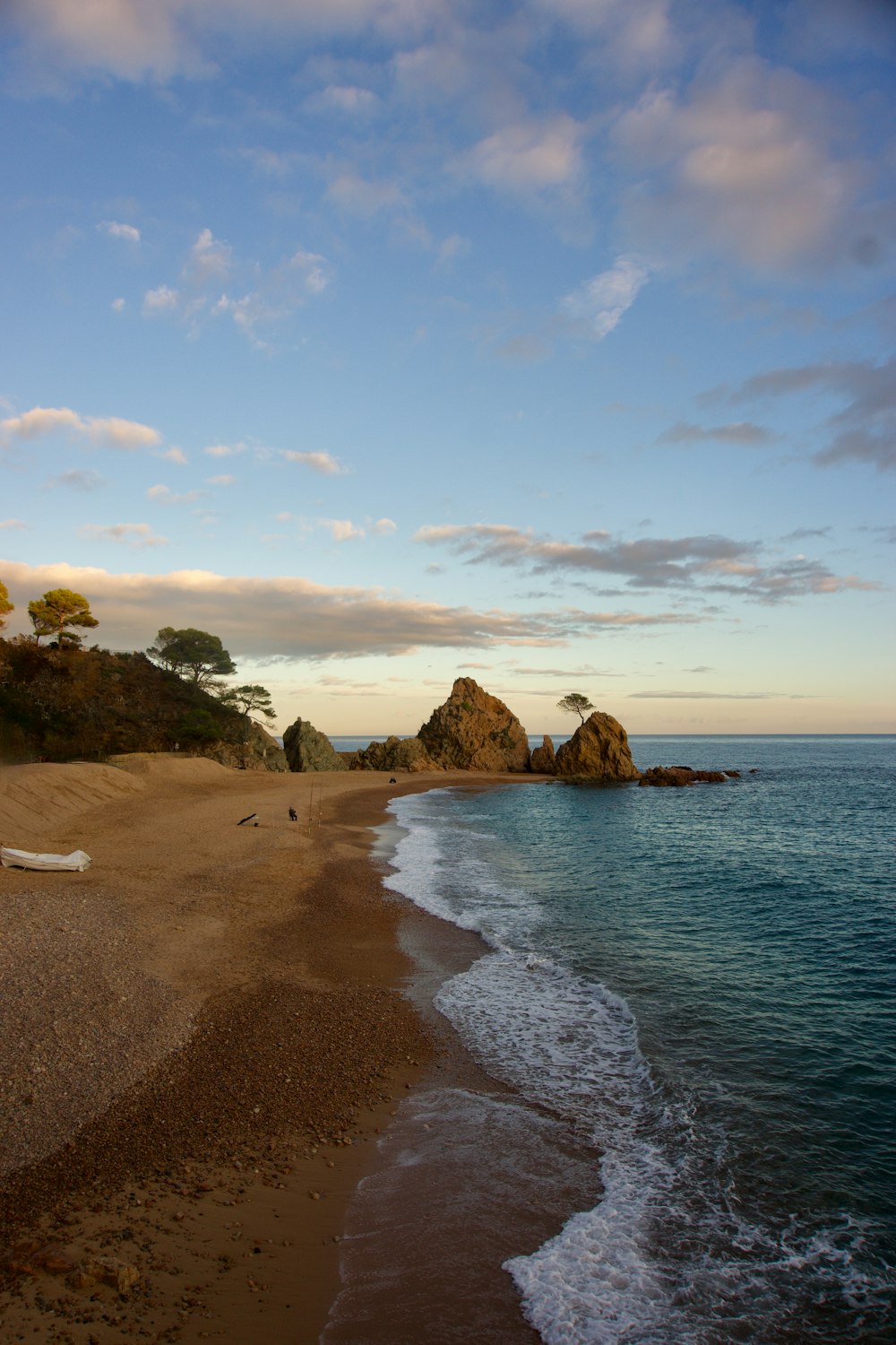 a sandy beach next to the ocean under a cloudy sky