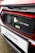 The image features a close-up of an electric car's charging port, with the Honda logo visible. The car is predominantly red with black and white accents. A sign with the text 'Swansway Motor Group' is prominently displayed below the charging area.