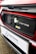 The image features a close-up of an electric car's charging port, with the Honda logo visible. The car is predominantly red with black and white accents. A sign with the text 'Swansway Motor Group' is prominently displayed below the charging area.
