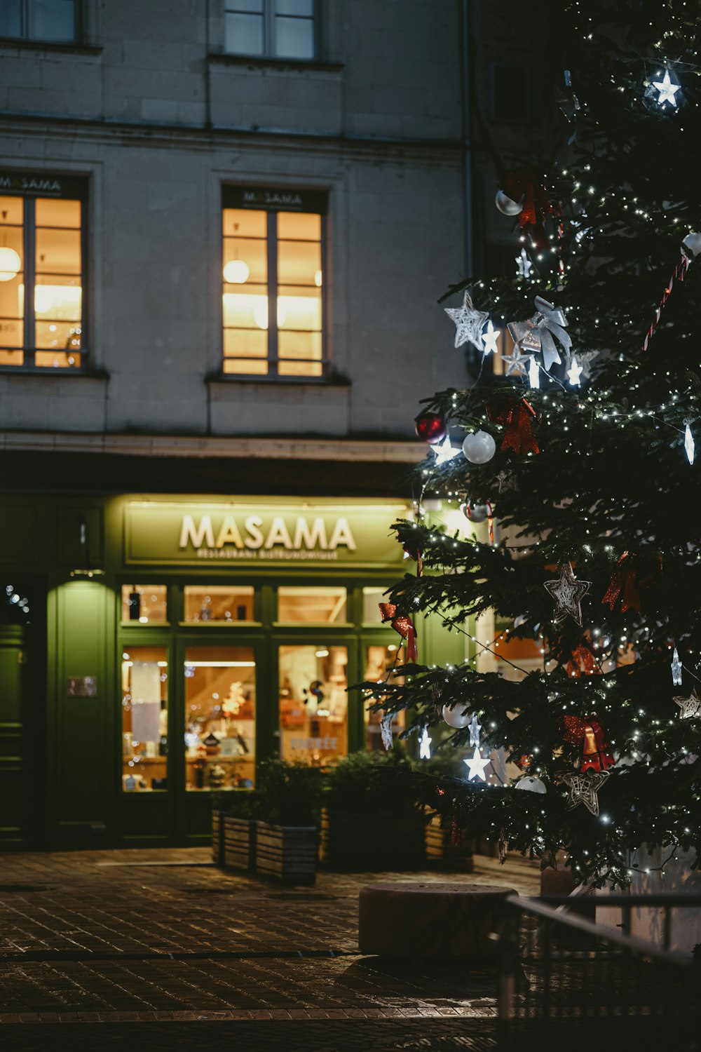 a christmas tree in front of a store at night