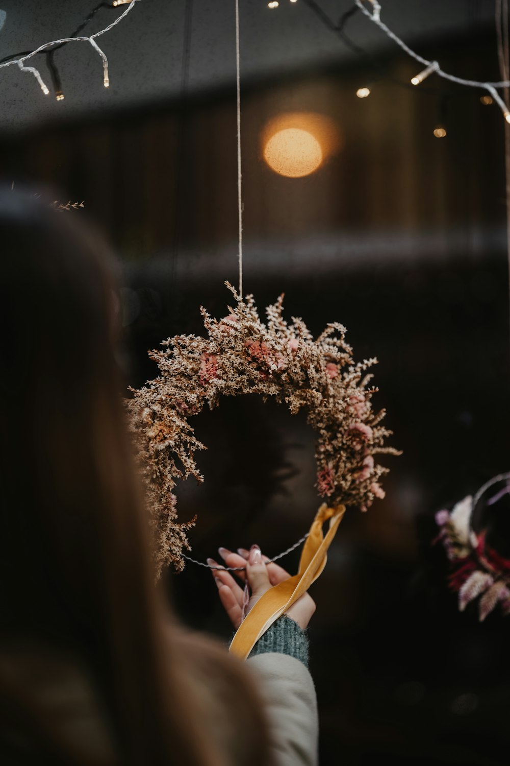 a woman holding a wreath with a yellow ribbon