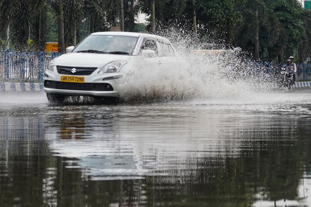 a white car driving through a flooded street